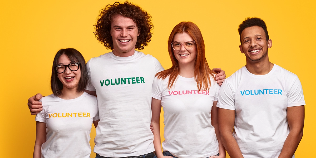 Grupa czterech wolontariuszy na żółtym tle